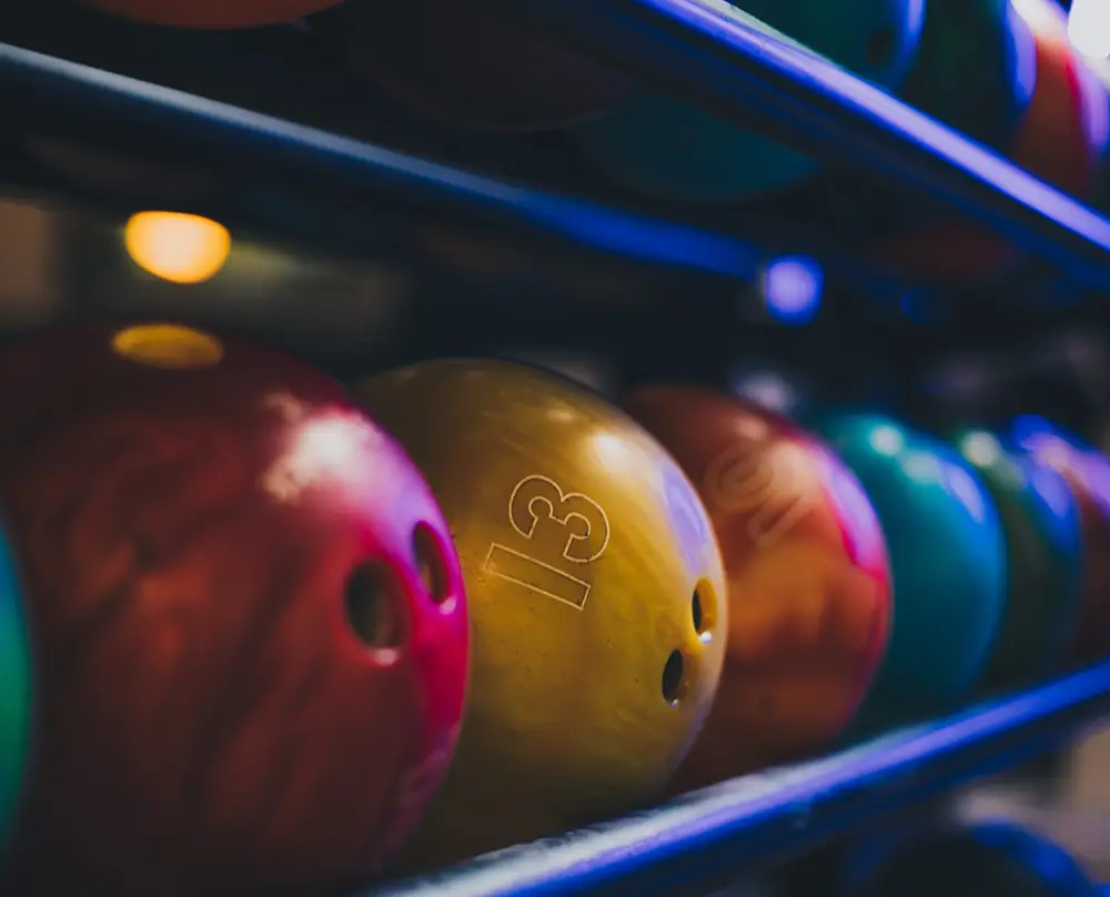 different colored bowling balls sitting on a rack